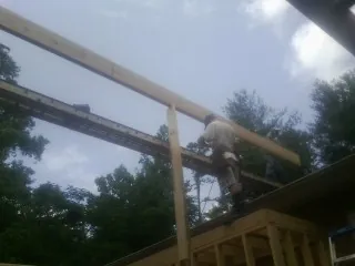 Carpenter setting a ridge beam over a new addition frame — Ice Dam Removal by Roofing Brothers in Marbury