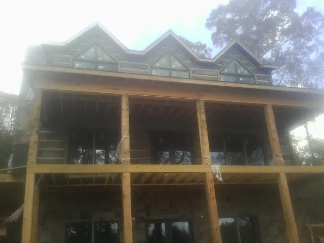 Dormers and porch framing on a large log home under construction — Roof Coating work by our crew in Marbury