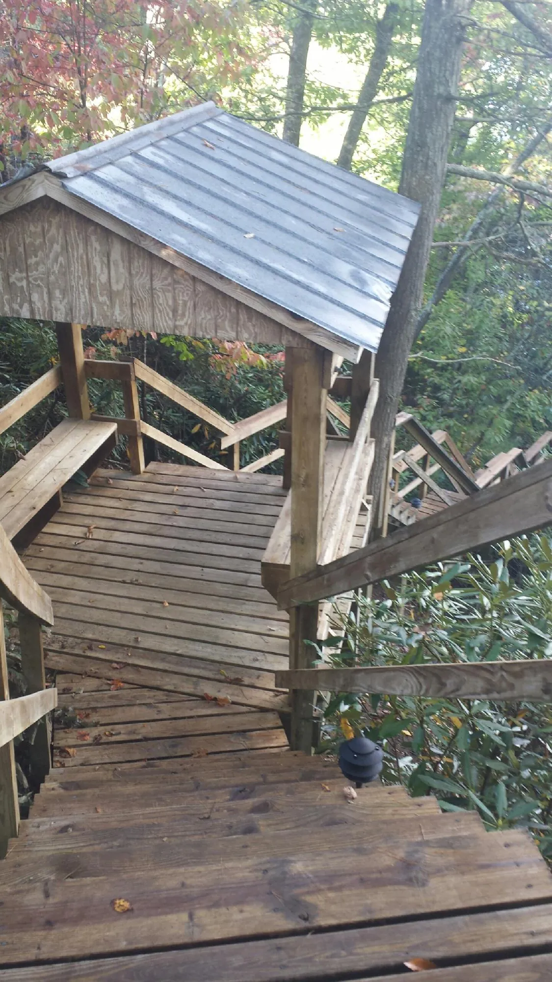 Metal roofed shelter over wooden steps on a wooded walkway — Skylight Repair & Installation work by our crew in Marbury
