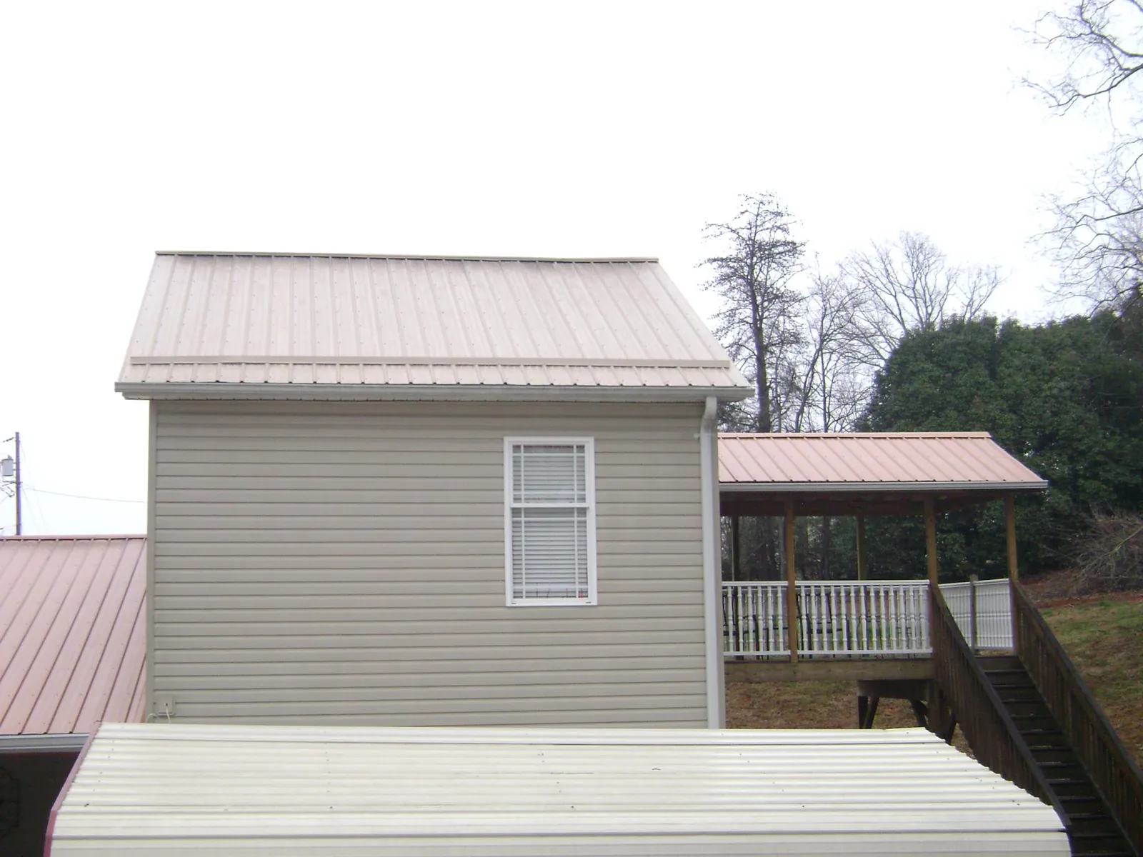 Tan metal roofs on a two story addition and attached porch, from a Roof Replacement job in Marbury