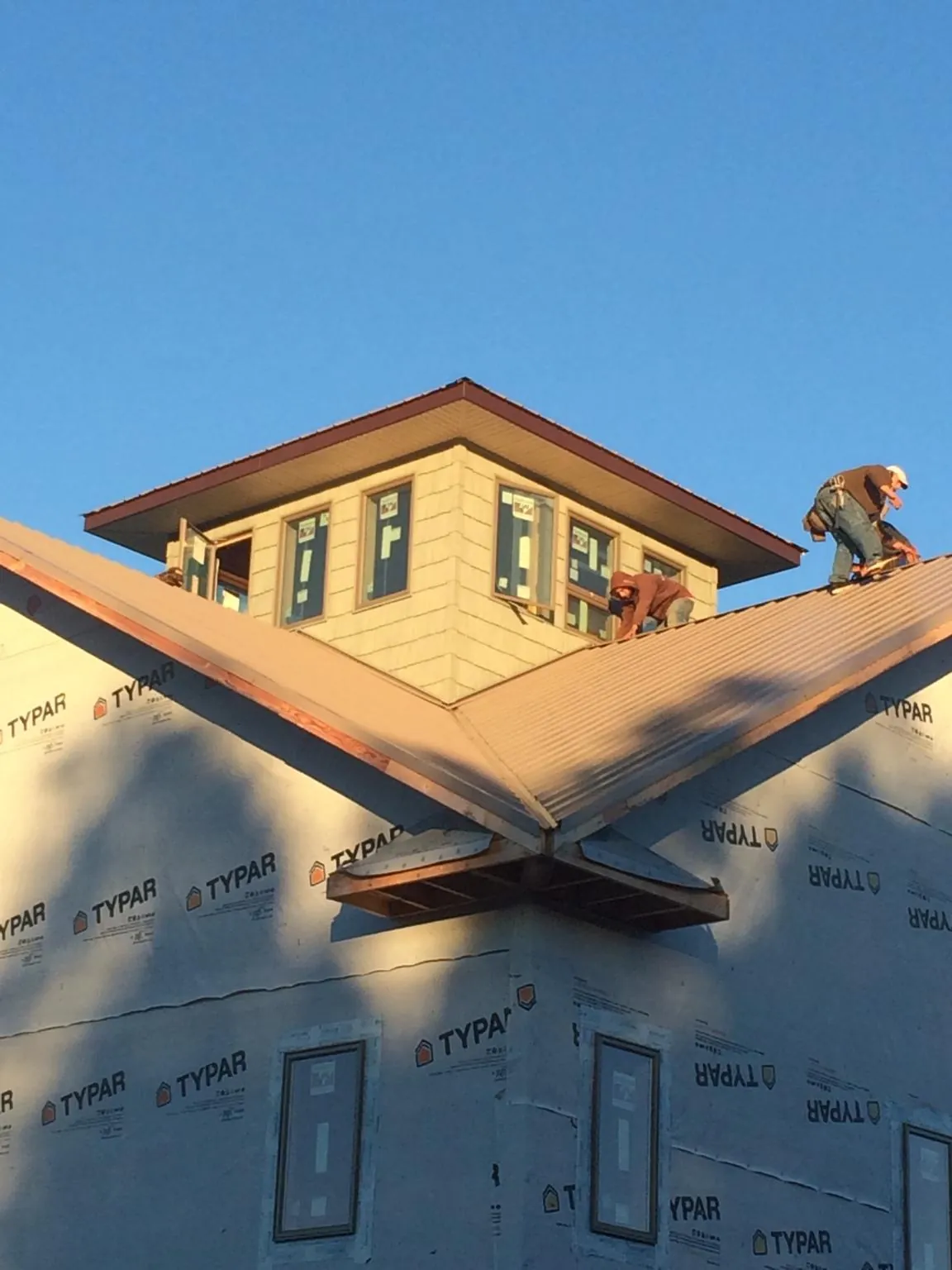 Roofers working around a rooftop cupola on a new metal roof at sunset — Roof Waterproofing in Marbury by Roofing Brothers